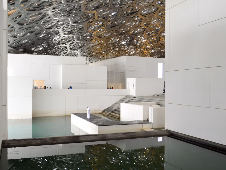 Cúpula rendilhada do Louvre Abu Dhabi sobre os pavilhões brancos e o espelho d'água