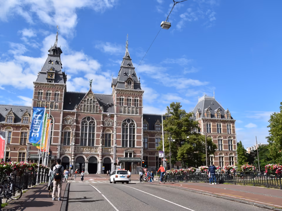 Fachada monumental do Rijksmuseum em Amsterdã, o prédio neorrenascentista de tijolos vermelhos com a passagem central em arco