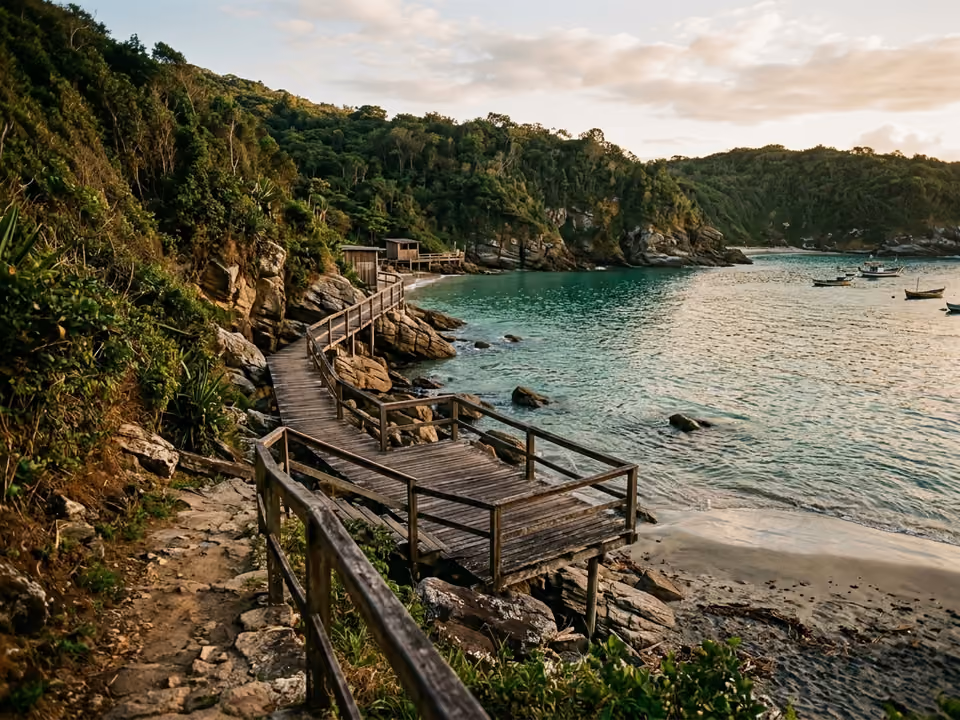Enseada da Praia do Forno com água verde calma e deck de madeira rústico sobre as pedras