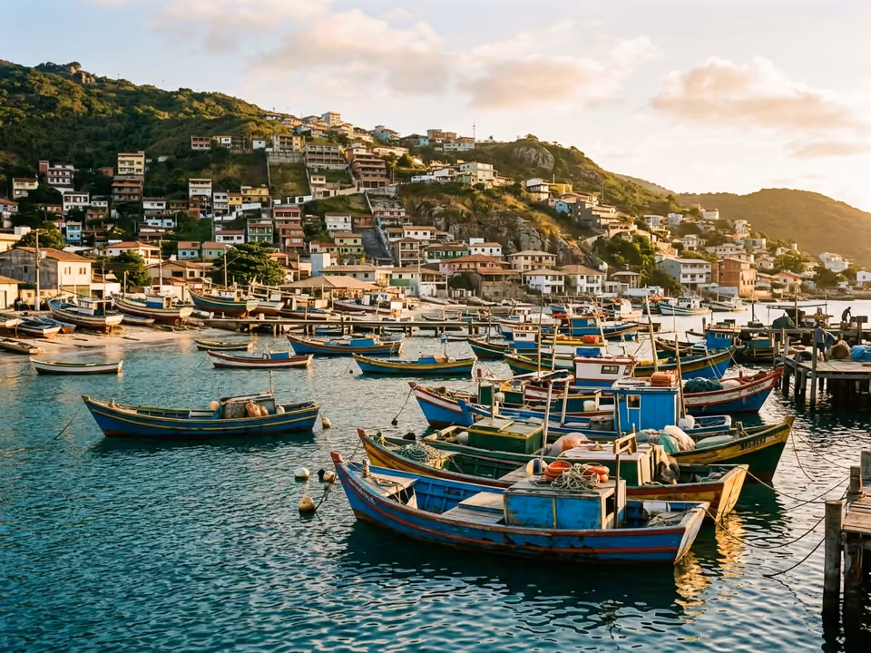 Barcos de pesca coloridos ancorados na Praia dos Anjos com a cidade subindo o morro