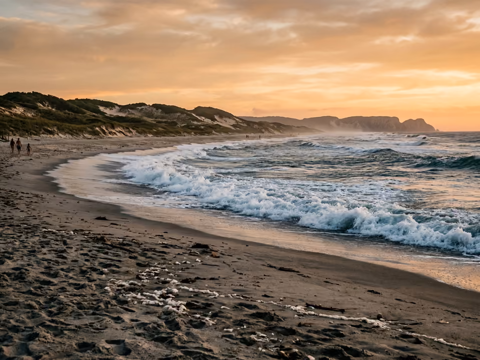 Praia Grande ao pôr do sol, faixa reta de areia com ondas fortes até o horizonte