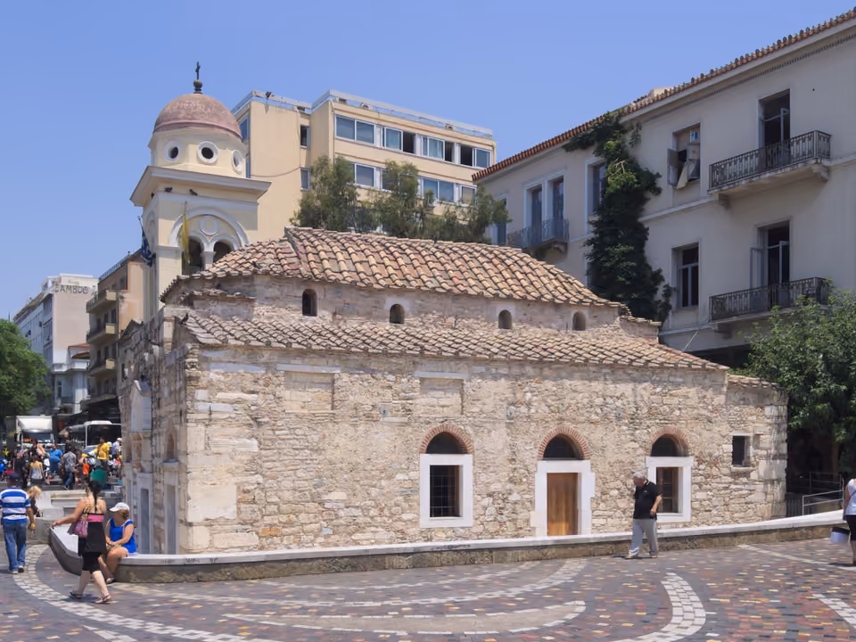 Praça Monastiraki em Atenas, com barracas de mercado, a mesquita histórica e a Acrópole visível ao fundo