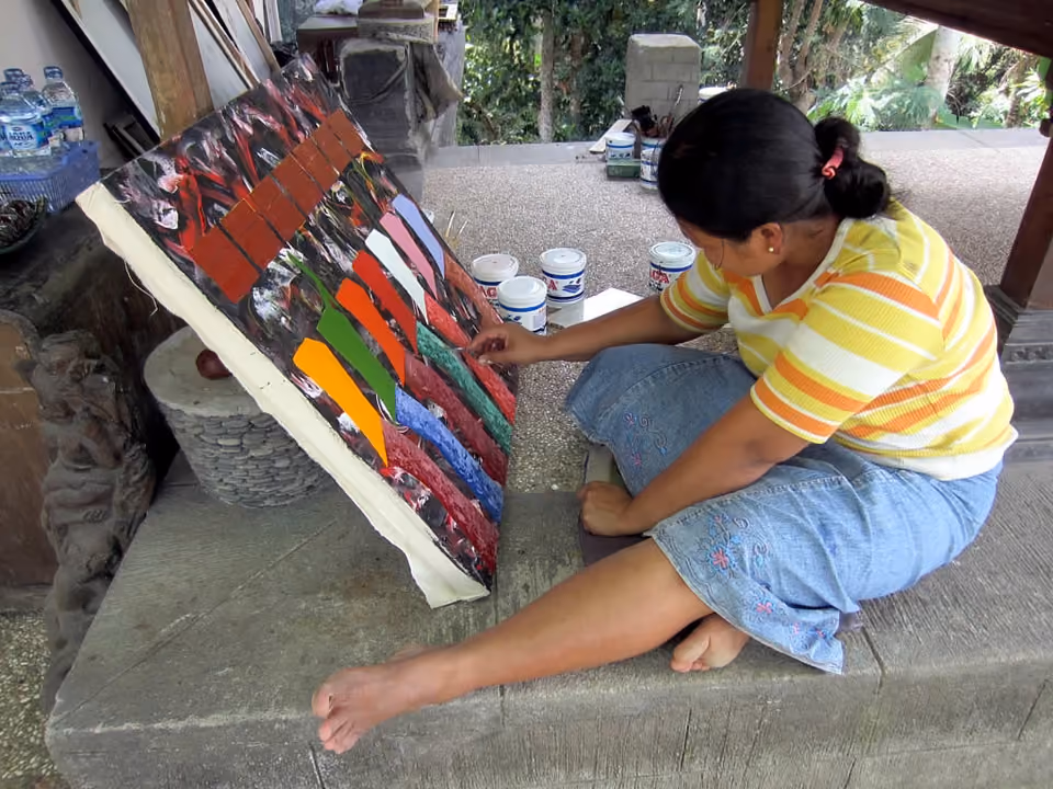 Pintor local trabalhando numa tela em ateliê de arte em Ubud, Bali