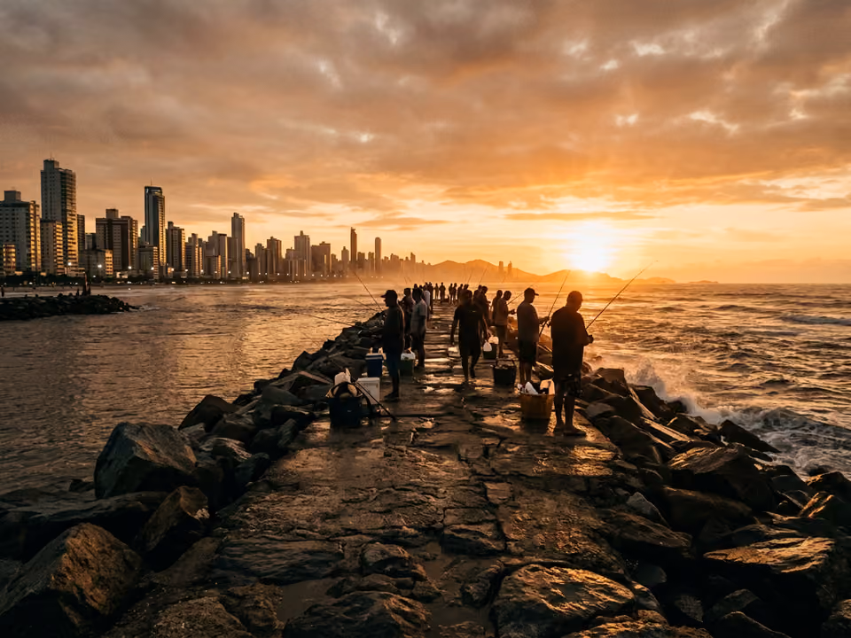 Molhe de pedra da Barra Sul ao pôr do sol, com silhuetas de pescadores e o rio encontrando o mar