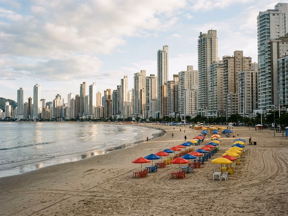 Faixa alargada da Praia Central pela manhã, com guarda-sóis e o paredão de arranha-céus atrás
