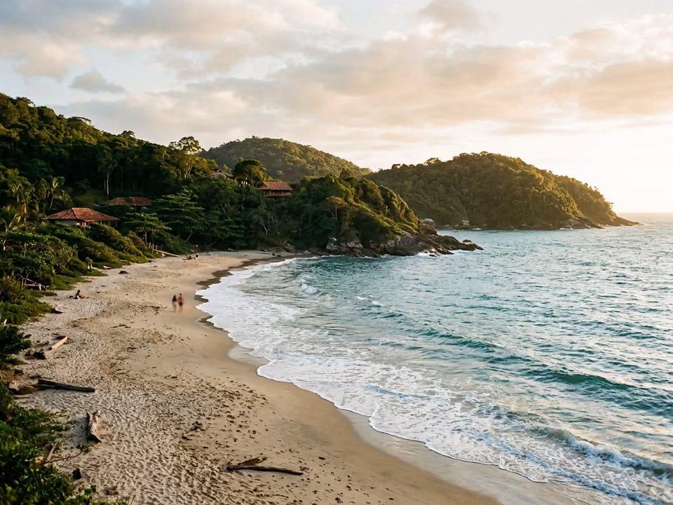 Enseada sossegada de Taquaras com sol da tarde, ondas suaves e costões verdes, sem prédios