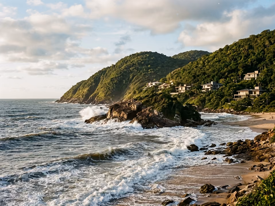 Mar bravo do Estaleiro com pontas de pedra e morros de vegetação com poucas casas sofisticadas