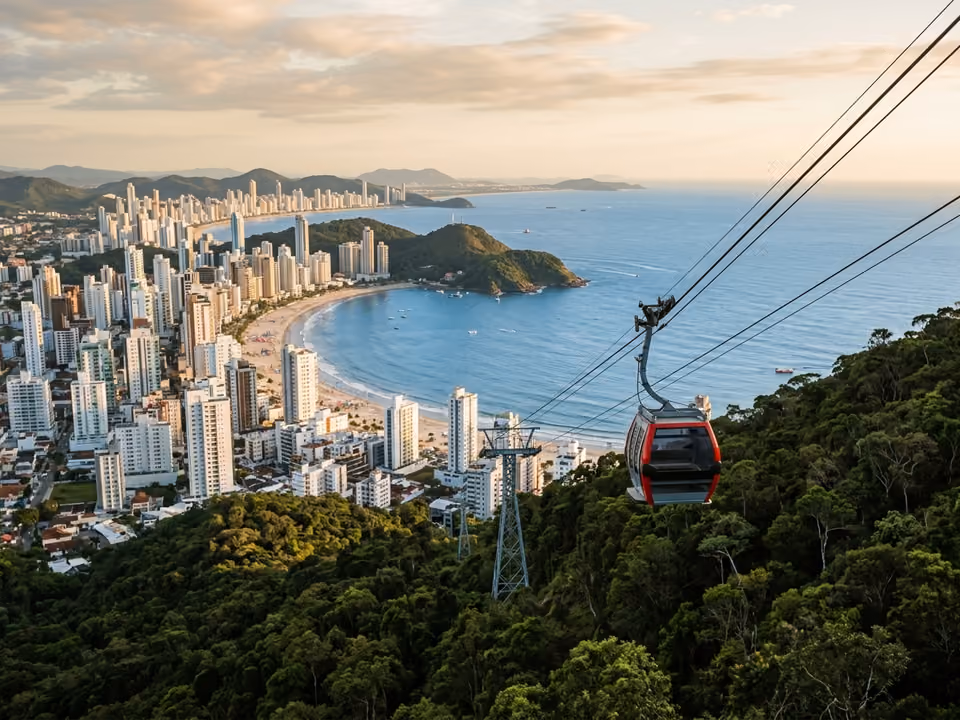 Bondinho do Unipraias cruzando alto sobre os morros de mata entre a cidade e o mar