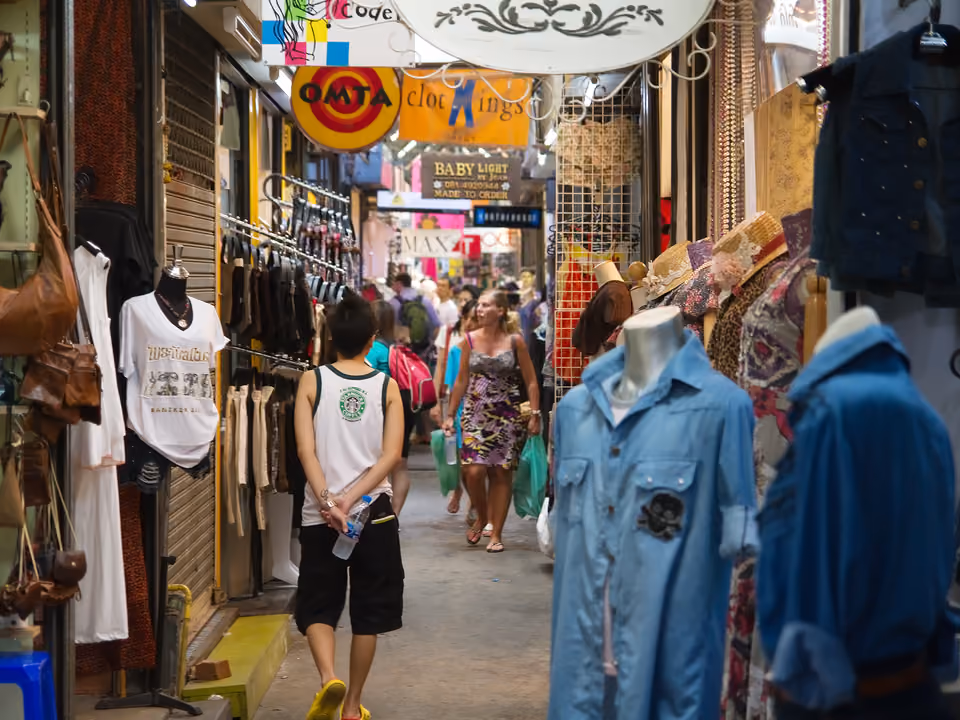 Corredor estreito de barracas do Mercado de Chatuchak, em Bangkok, lotado de gente e mercadoria