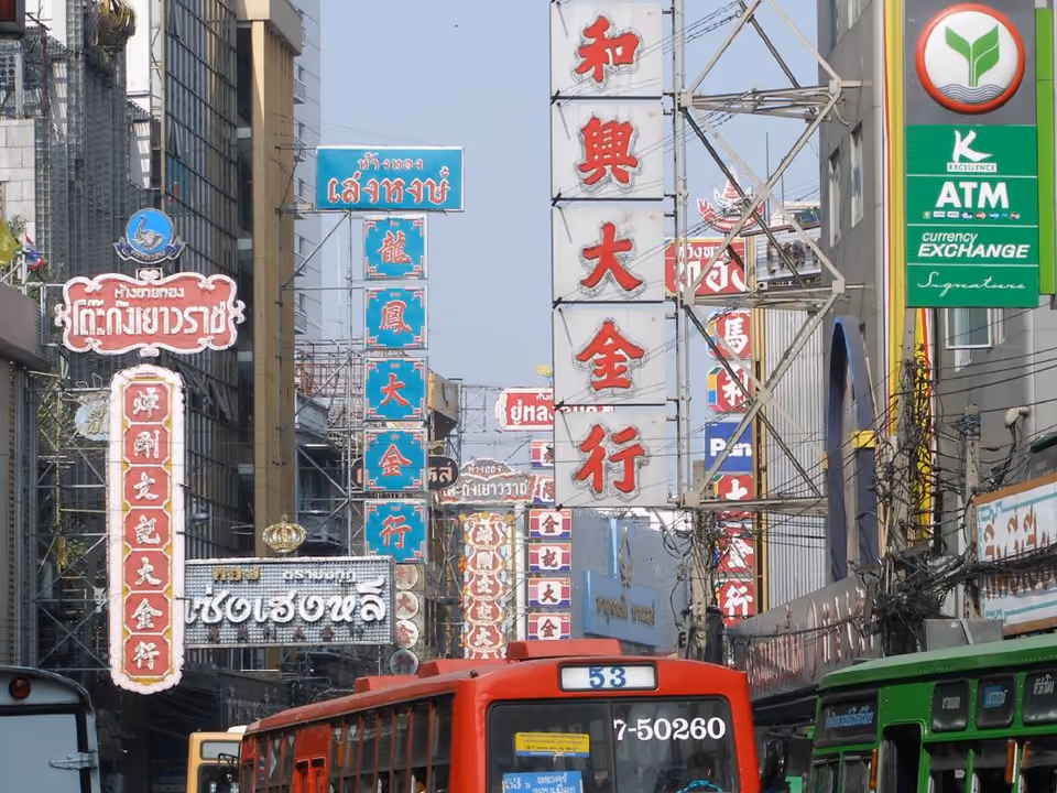 Rua de Yaowarat, o Chinatown de Bangkok, com letreiros verticais em chinês e ônibus circulando