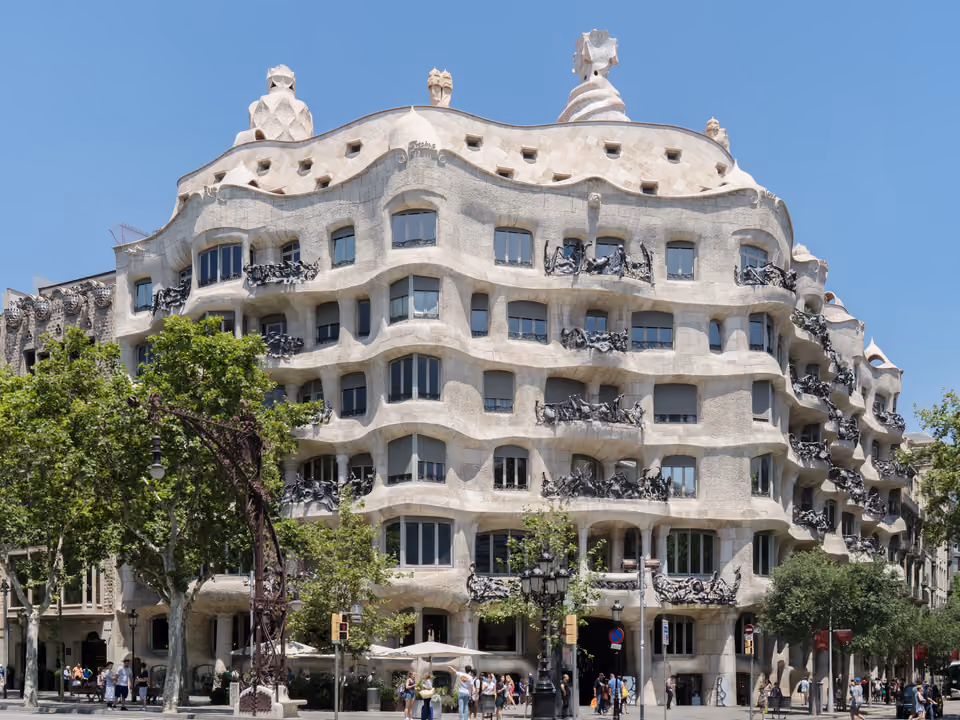 Fachada de pedra ondulada da Casa Milà (La Pedrera) em Barcelona, com as varandas de ferro retorcido e as chaminés no terraço, vista da esquina do Passeig de Gràcia