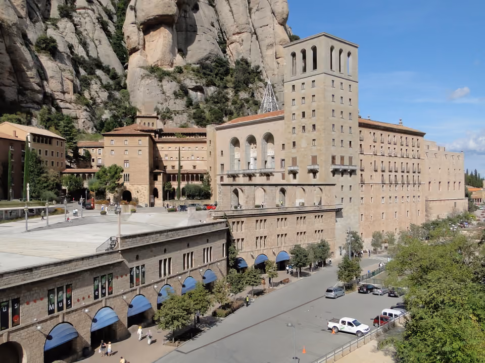 Mosteiro de Santa Maria de Montserrat encravado ao pé dos picos de rocha arredondada da montanha, na Catalunha, com a torre do campanário e o edifício do museu