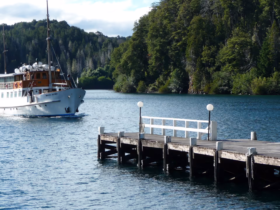 Catamarã navegando pelo Lago Nahuel Huapi em direção à Isla Victoria, cercado por montanhas arborizadas