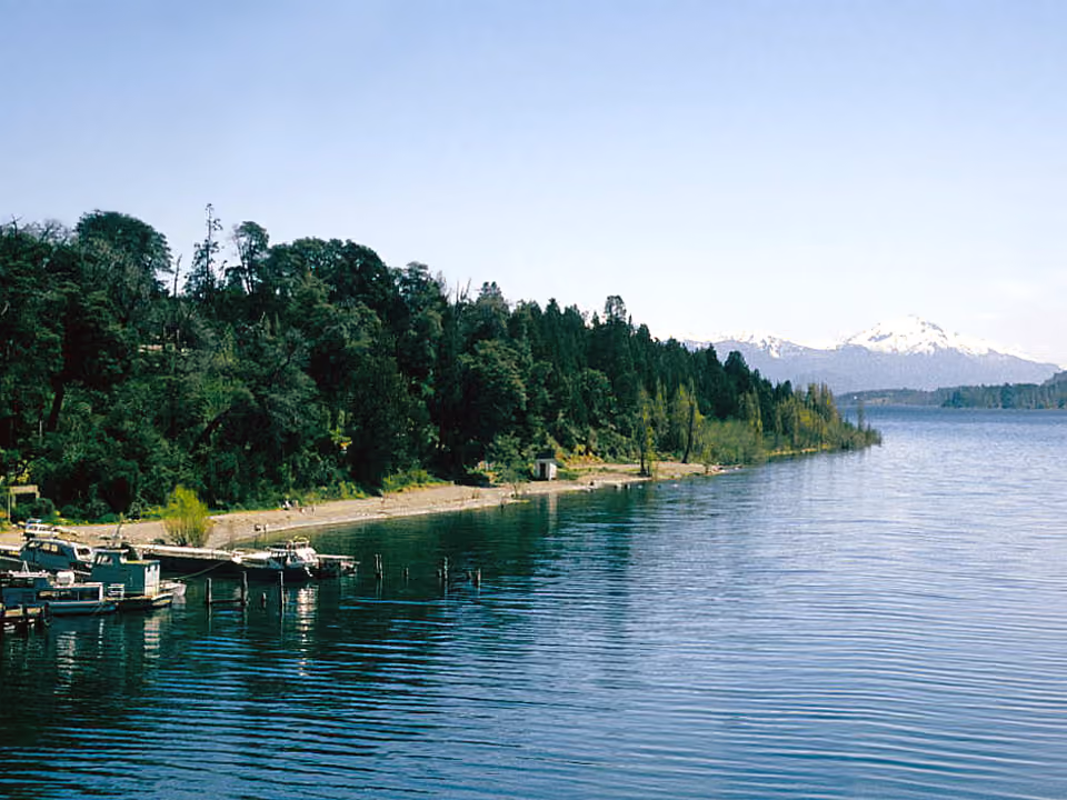 Playa Bonita, em Bariloche, praia de pedras à beira do Lago Nahuel Huapi ao entardecer, com montanhas ao fundo