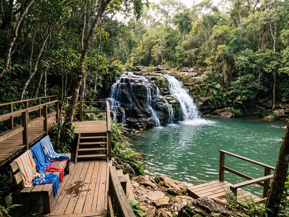 Uma das cachoeiras da Estância Mimosa caindo em poço de água esverdeada, com banhistas na borda cercados pela mata