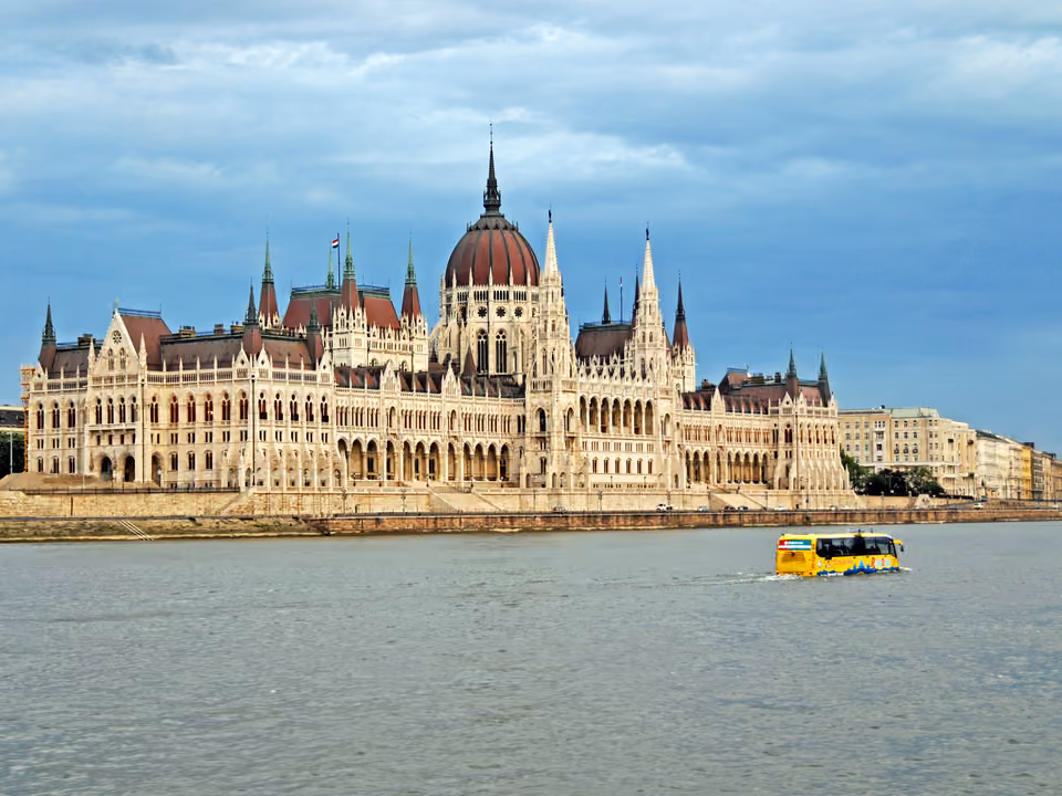 Barco de cruzeiro turístico navegando pelo rio Danúbio em Budapeste à noite, com o Parlamento iluminado ao fundo