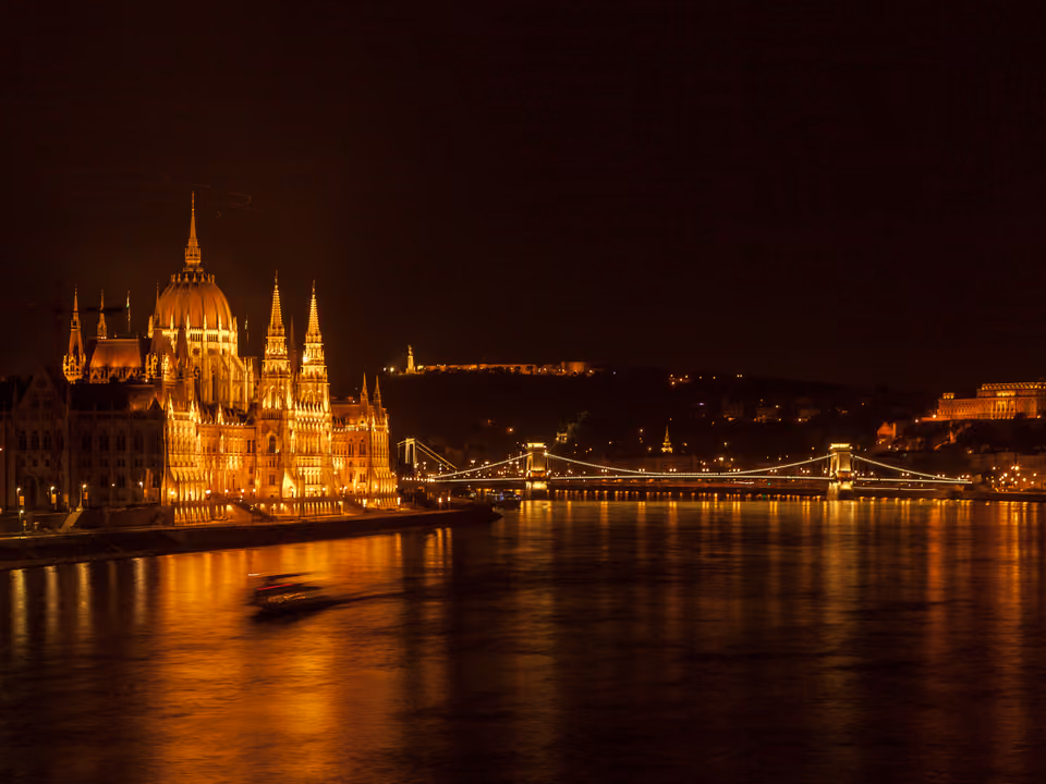 Fachada neogótica do Parlamento Húngaro à beira do rio Danúbio em Budapeste, com as torres pontiagudas e a cúpula central