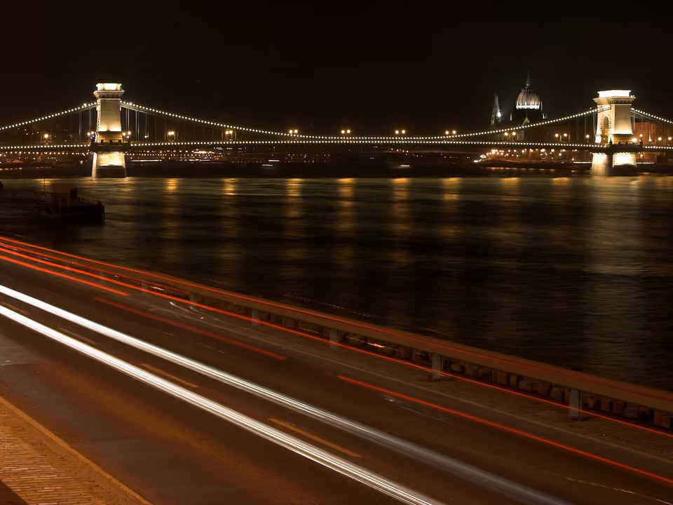 Ponte das Correntes em Budapeste, iluminada à noite, com os leões de pedra na entrada e o rio Danúbio abaixo
