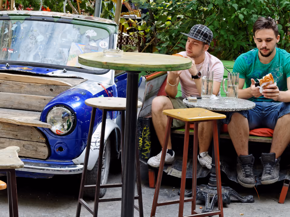 Interior do ruin bar Szimpla Kert em Budapeste, com decoração eclética, plantas e móveis reaproveitados no pátio