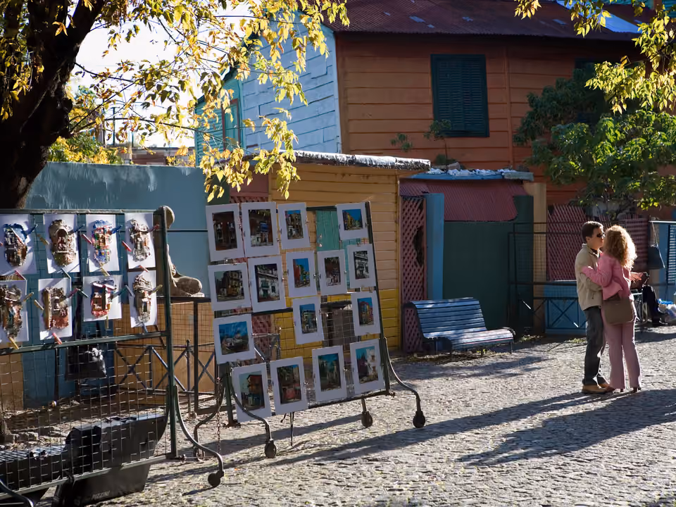 Caminito em La Boca, casas de zinco coloridas ladeando a rua-museu a céu aberto, com banca de arte na calçada