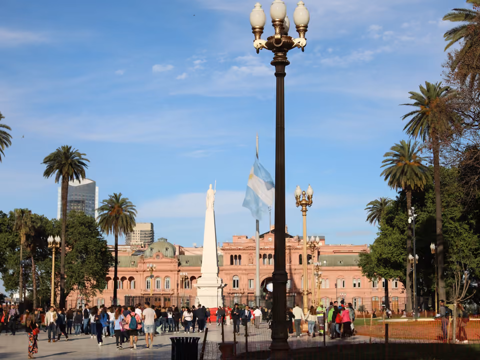 Fachada rosa da Casa Rosada vista da Plaza de Mayo, com a Pirámide de Mayo e a bandeira argentina em primeiro plano