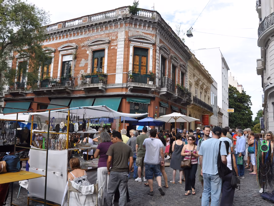 Barracas de antiguidades e multidão na Plaza Dorrego durante a Feira de San Telmo, com o casario histórico ao redor