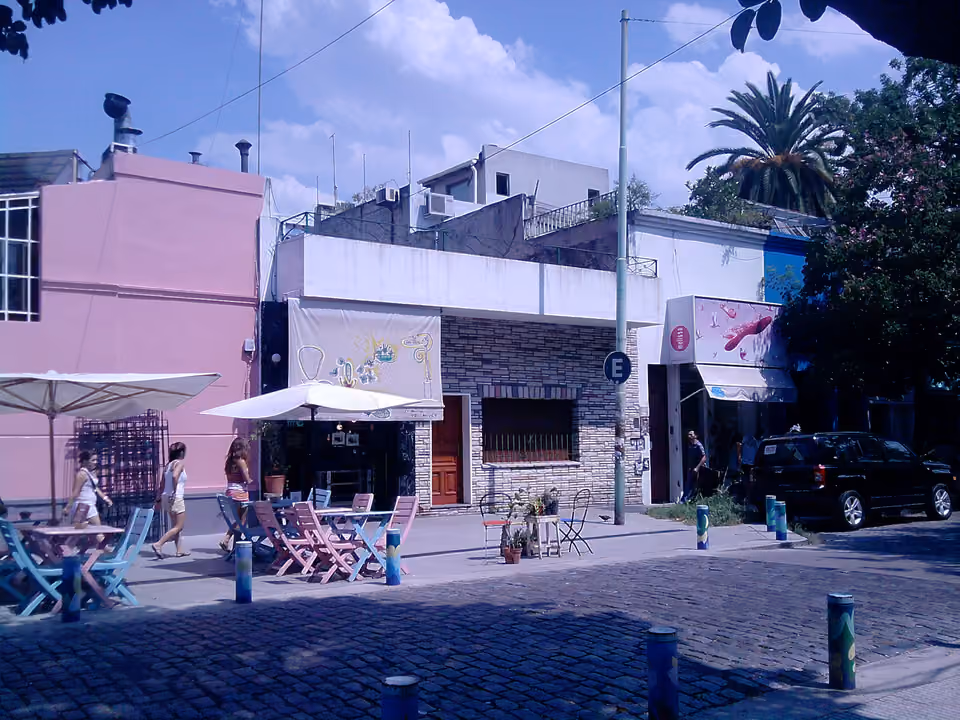 Rua de Palermo Soho com casas baixas reformadas em lojas e cafés, mesas e guarda-sóis na calçada
