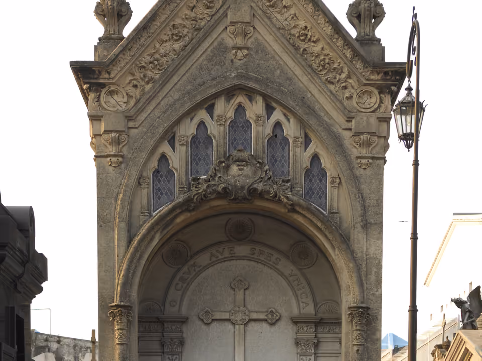 Mausoléu ornamentado em estilo gótico no Cemitério da Recoleta, com vitrais e cruz esculpida em mármore
