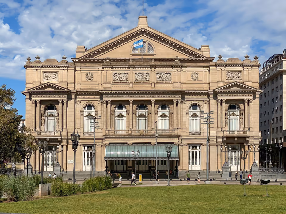 Fachada neoclássica do Teatro Colón, com a bandeira argentina no frontão e o jardim em frente