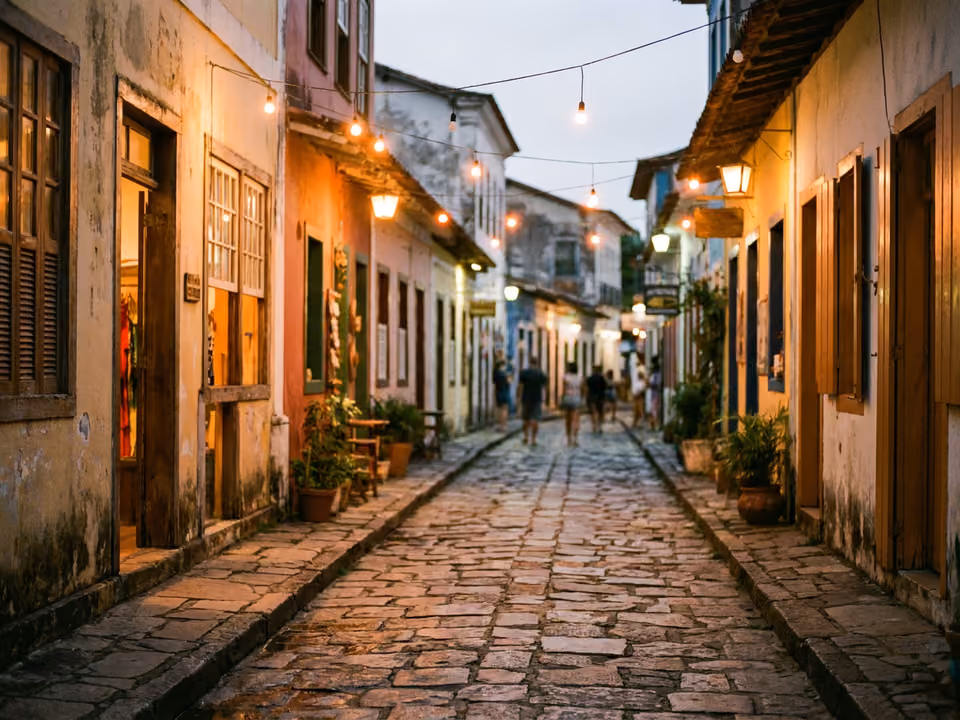 Rua de pedras irregulares ao anoitecer com casarios de vila de pescadores convertidos em lojas, em Búzios