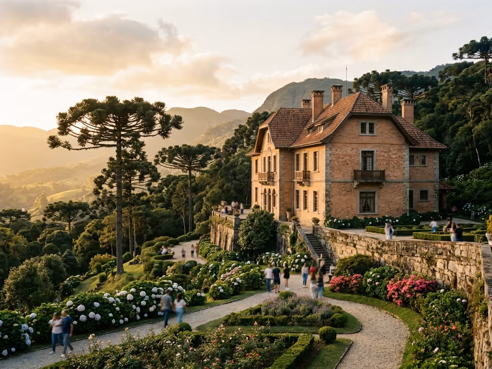 Fachada de tijolos do Palácio Boa Vista no alto da colina, com jardins e araucárias