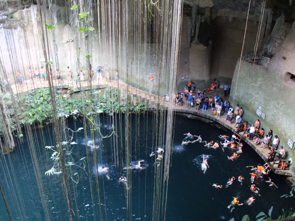 Cenote Ik Kil, poço circular de água doce turquesa cercado por paredes de pedra calcária cobertas de vegetação e raízes penduradas