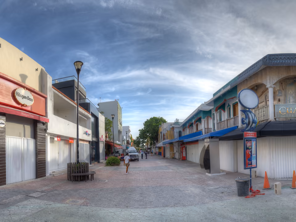 Quinta Avenida em Playa del Carmen, rua de pedestres com lojas, restaurantes e placas coloridas dos dois lados