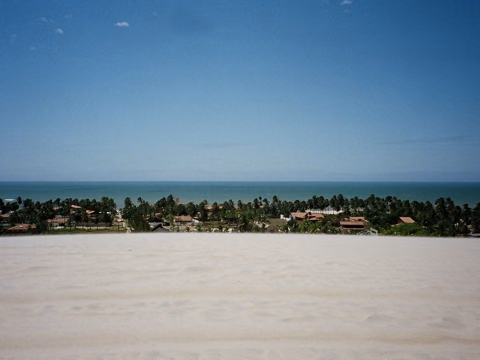 Duna de areia com vista para vila costeira e mar no litoral do Ceará
