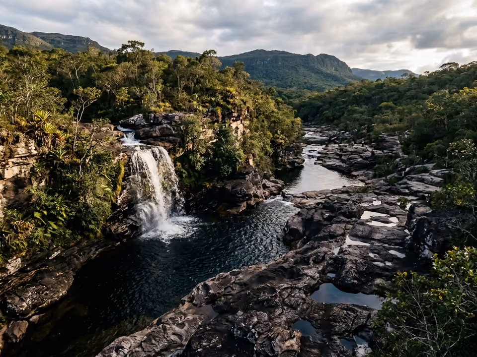 Poços do rio Mucugezinho entre lajes escuras de pedra com cachoeira, na luz da tarde