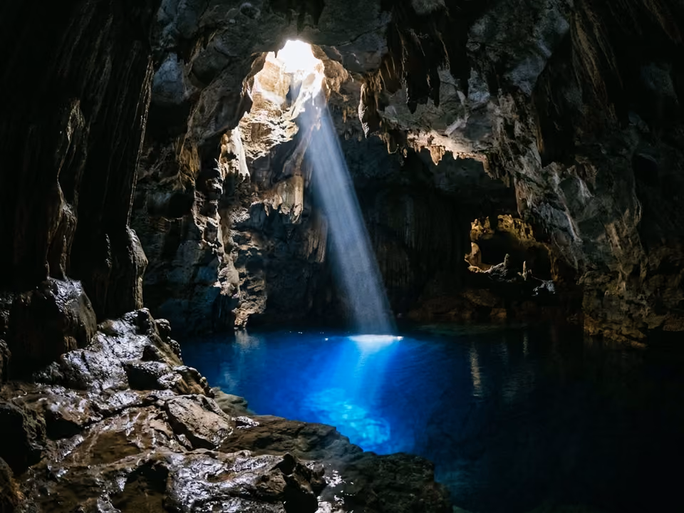 Facho de luz atravessando a escuridão da caverna e tingindo de azul o poço parado do Poço Encantado