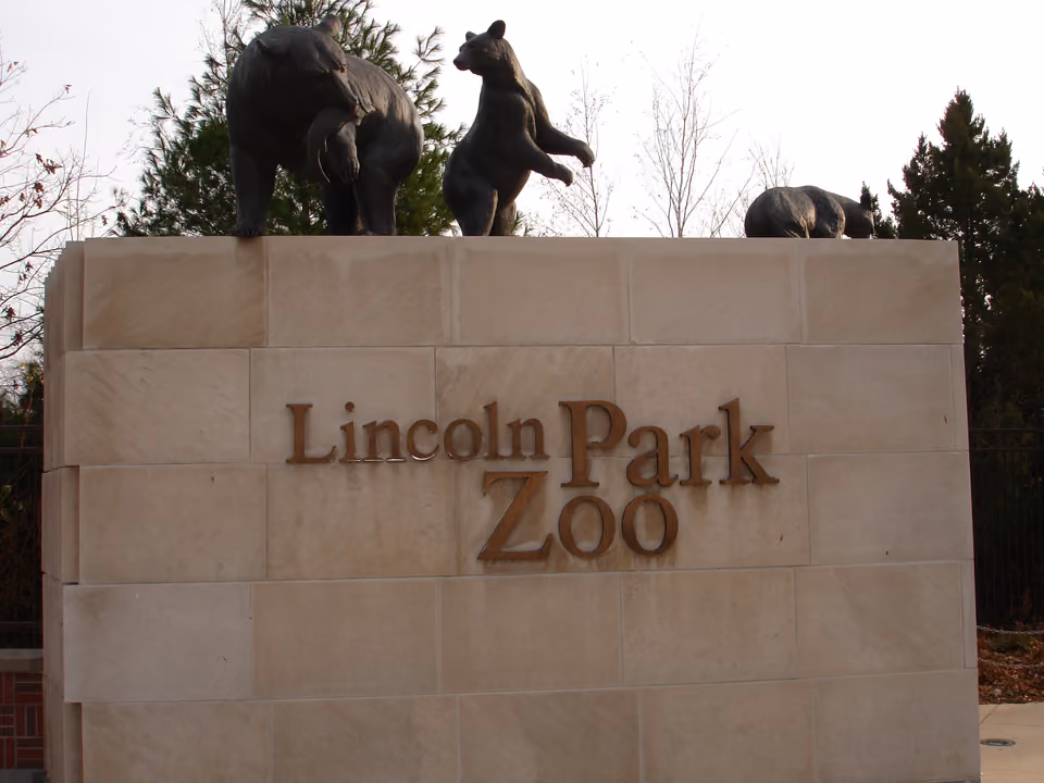 Entrada do Lincoln Park Zoo em Chicago, com vegetação e placa de boas-vindas ao zoológico gratuito