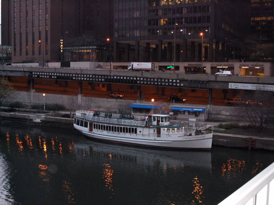 Barco de passeio navegando pelo Chicago River ao entardecer, entre os arranha-céus do centro
