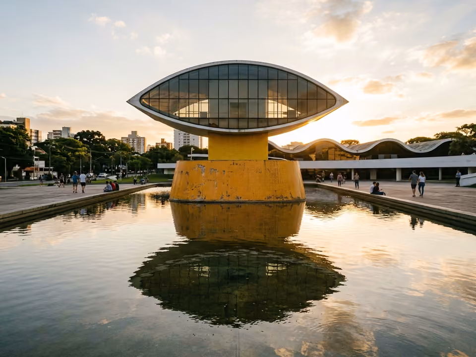 Torre em formato de olho do Museu Oscar Niemeyer refletida no espelho d'água ao entardecer