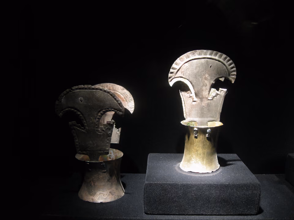 Peças de ourivesaria pré-colombiana em exposição no Museu de Arte Pré-Colombiana de Cusco, com iluminação de destaque contra fundo escuro