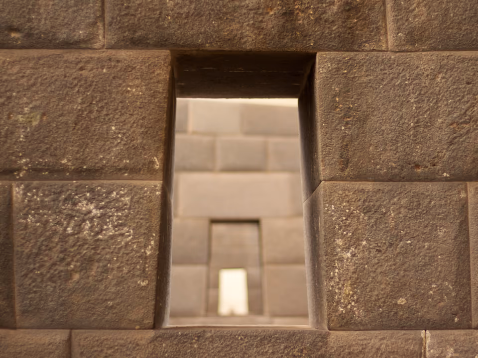 Muro de pedra inca perfeitamente encaixada do Qorikancha, em Cusco, com a base curva original visível sob a construção colonial