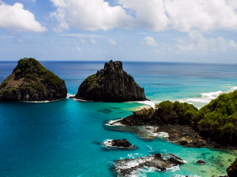 Baía dos Porcos em Fernando de Noronha, as piscinas naturais entre as rochas vulcânicas na maré baixa, com os dois picos do Morro Dois Irmãos logo à frente