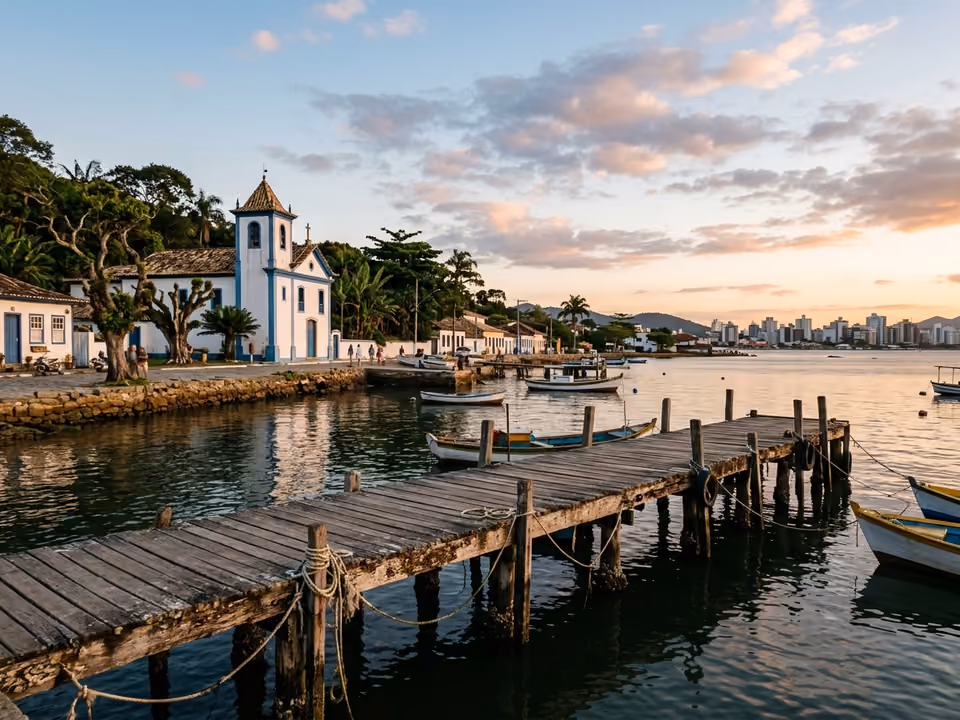Píer de Santo Antônio de Lisboa ao pôr do sol sobre a água calma, com igrejinha açoriana e figueiras
