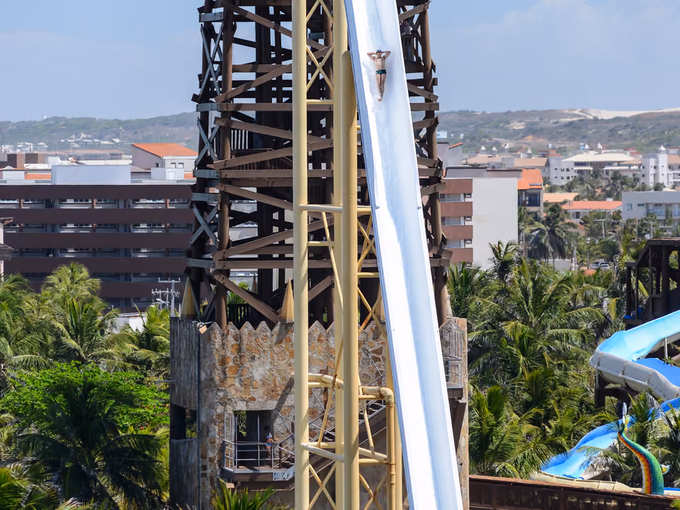 Torre do escorregador Insano do Beach Park, em Fortaleza, com um visitante descendo e escorregadores coloridos ao fundo