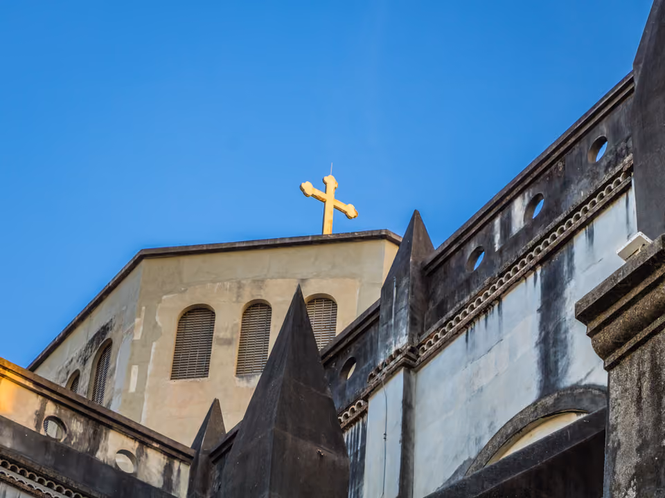 Detalhe da torre e da cruz da Catedral Metropolitana de Fortaleza, com a fachada neogótica de concreto contra o céu azul