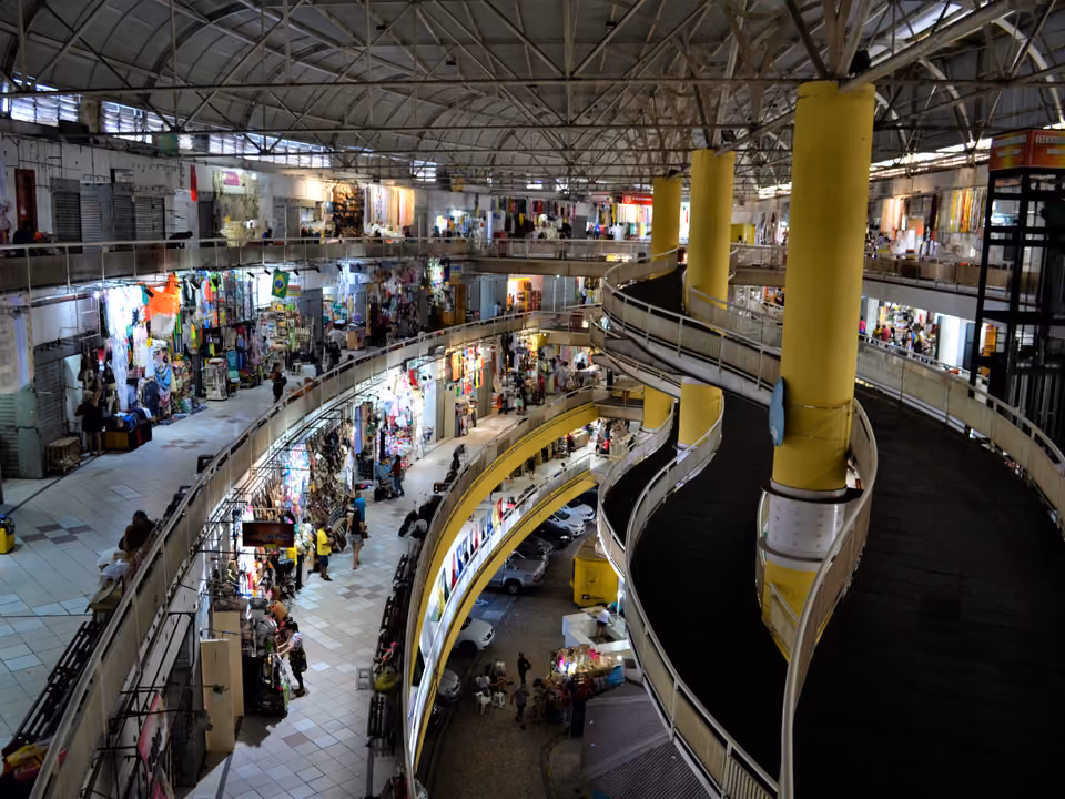 Vista interna de vários andares do Mercado Central de Fortaleza, com rampas curvas, pilares amarelos e lojas de artesanato