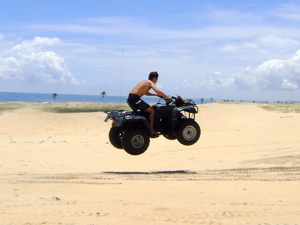 Veículo off-road subindo uma duna de areia branca em Cumbuco, no Ceará, com o mar ao fundo