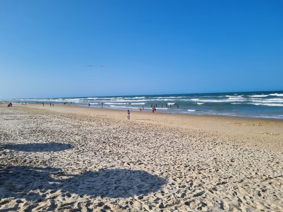 Praia do Futuro em Fortaleza, faixa de areia larga com banhistas na arrebentação em dia de sol