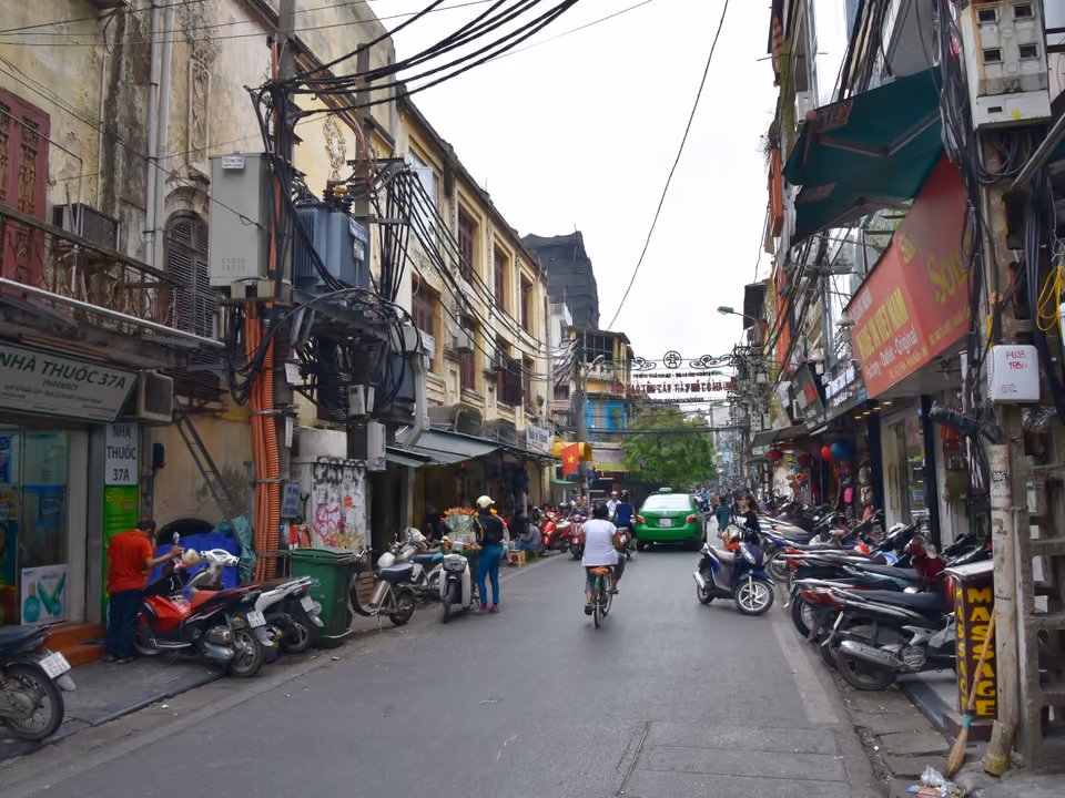 Rua estreita do Casco Antigo de Hanói, cheia de motocicleta e fiação aérea, Vietnã