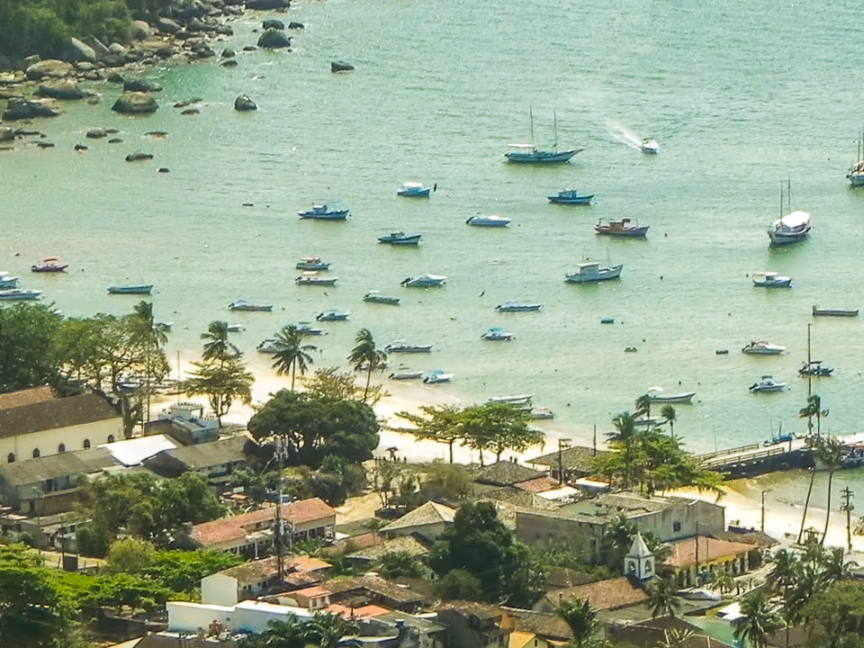 Vila do Abraão vista da praia, com casas baixas e coloridas e montanha ao fundo